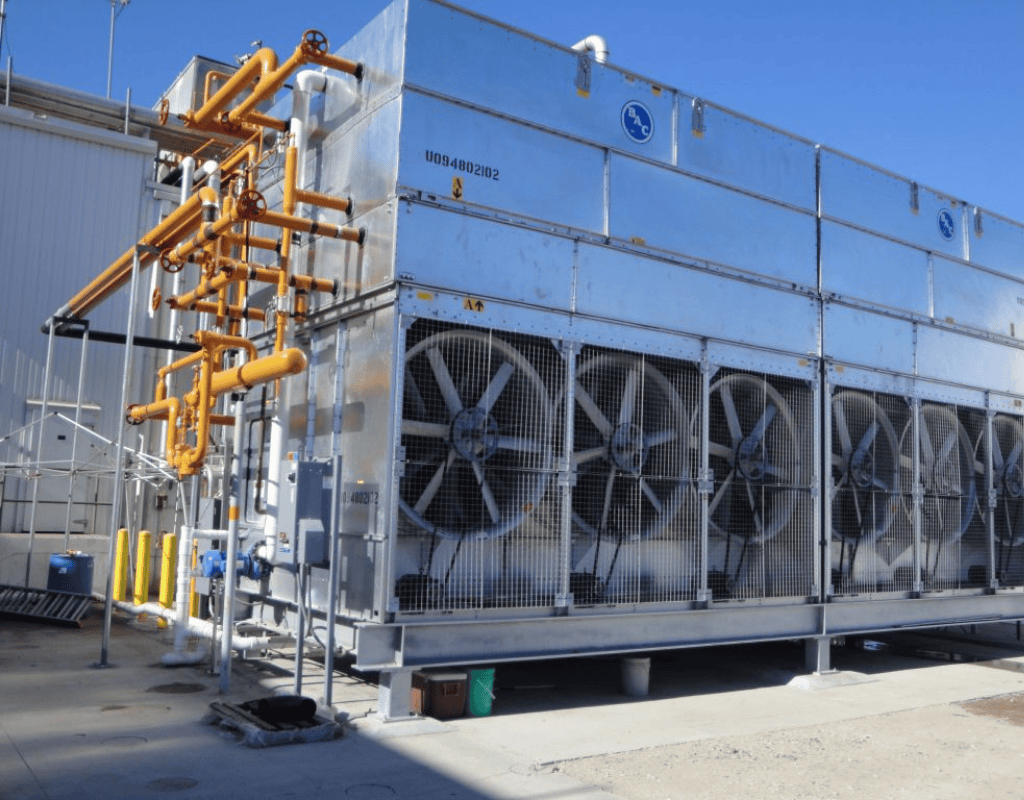 Large outdoor industrial refrigeration condenser with multiple fans and piping at a Southern New England facility.